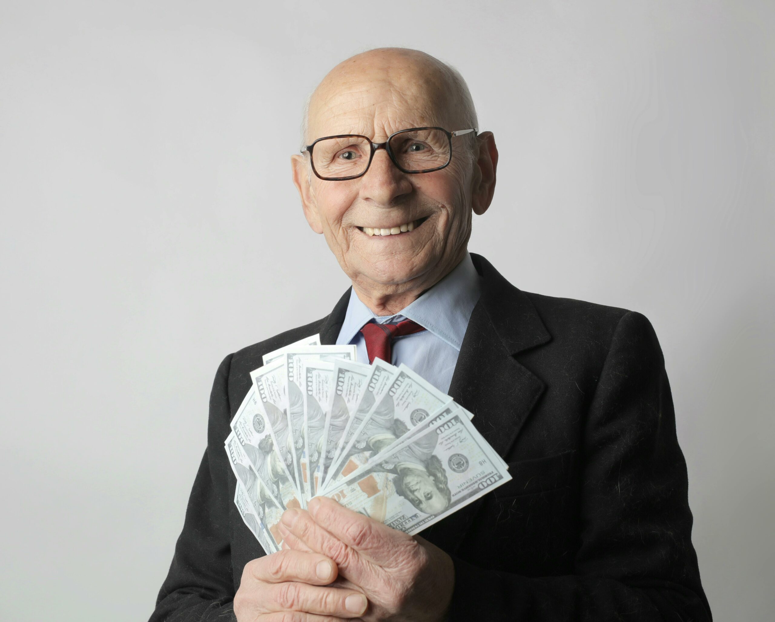 Mężczyzna w garniturze trzymający plik banknotów – symbol zarabiania online.